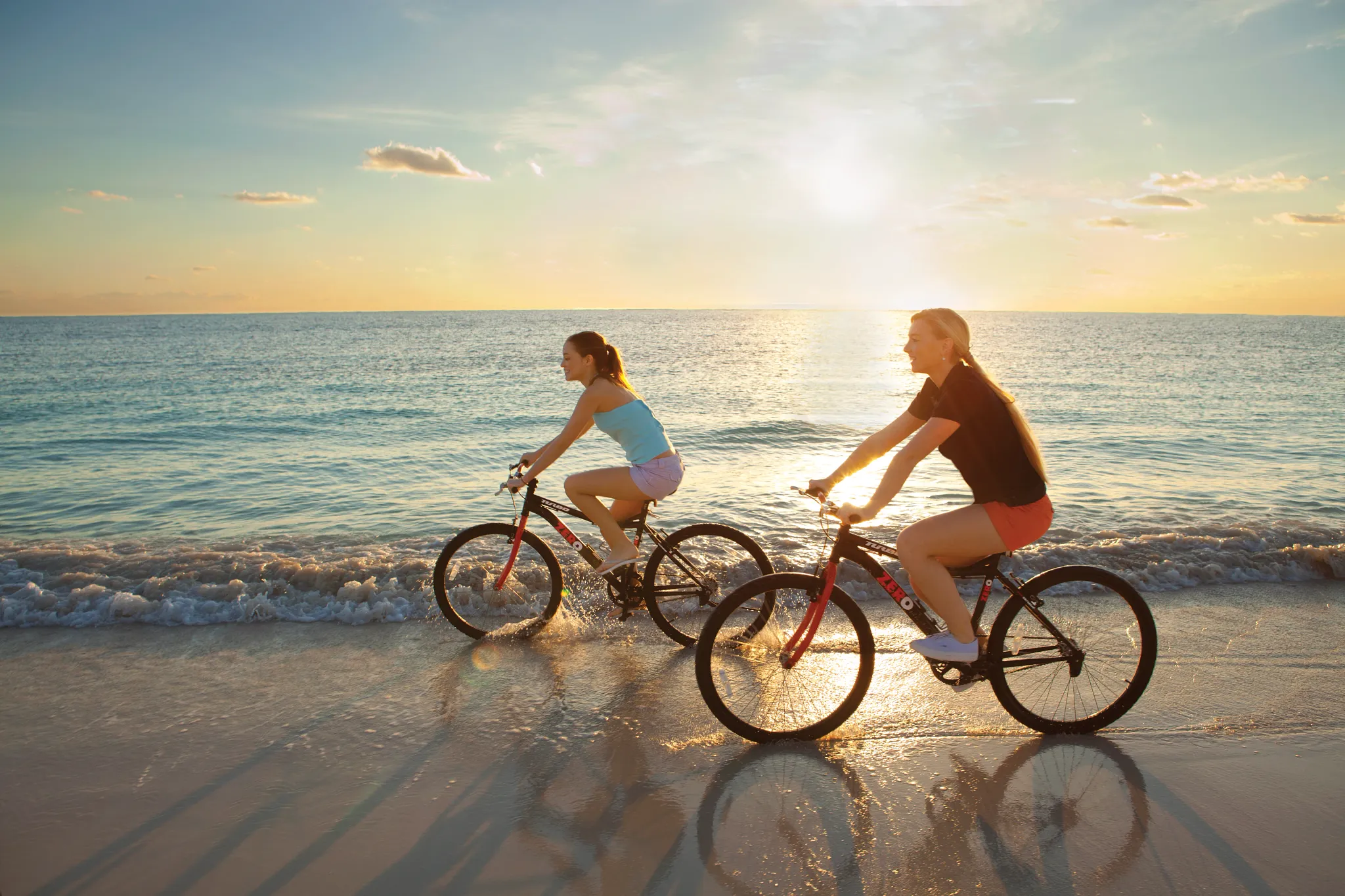 Girls riding bicycles along the beach at Dreams Sapphire Resort & Spa during a sunny Riviera Maya afternoon.