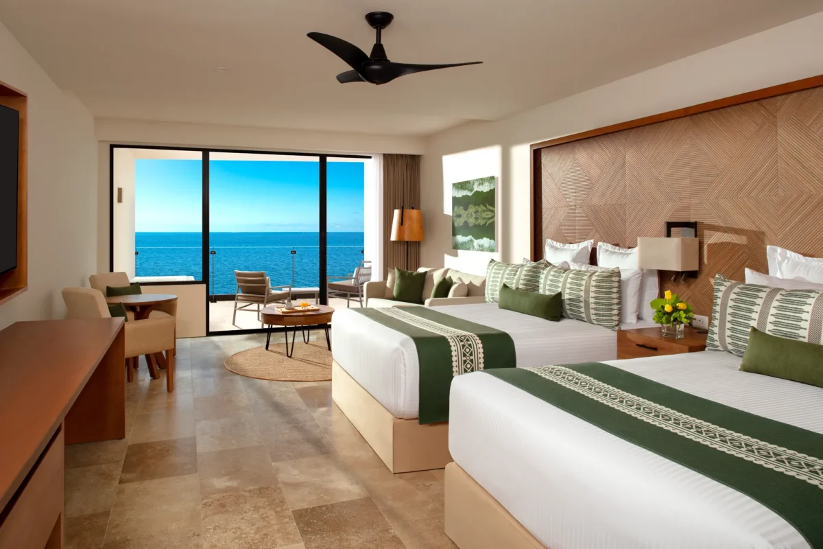 Club Junior Suite Ocean Front Double with two double beds, seating area, and Caribbean Sea views at Dreams Sapphire Resort & Spa.