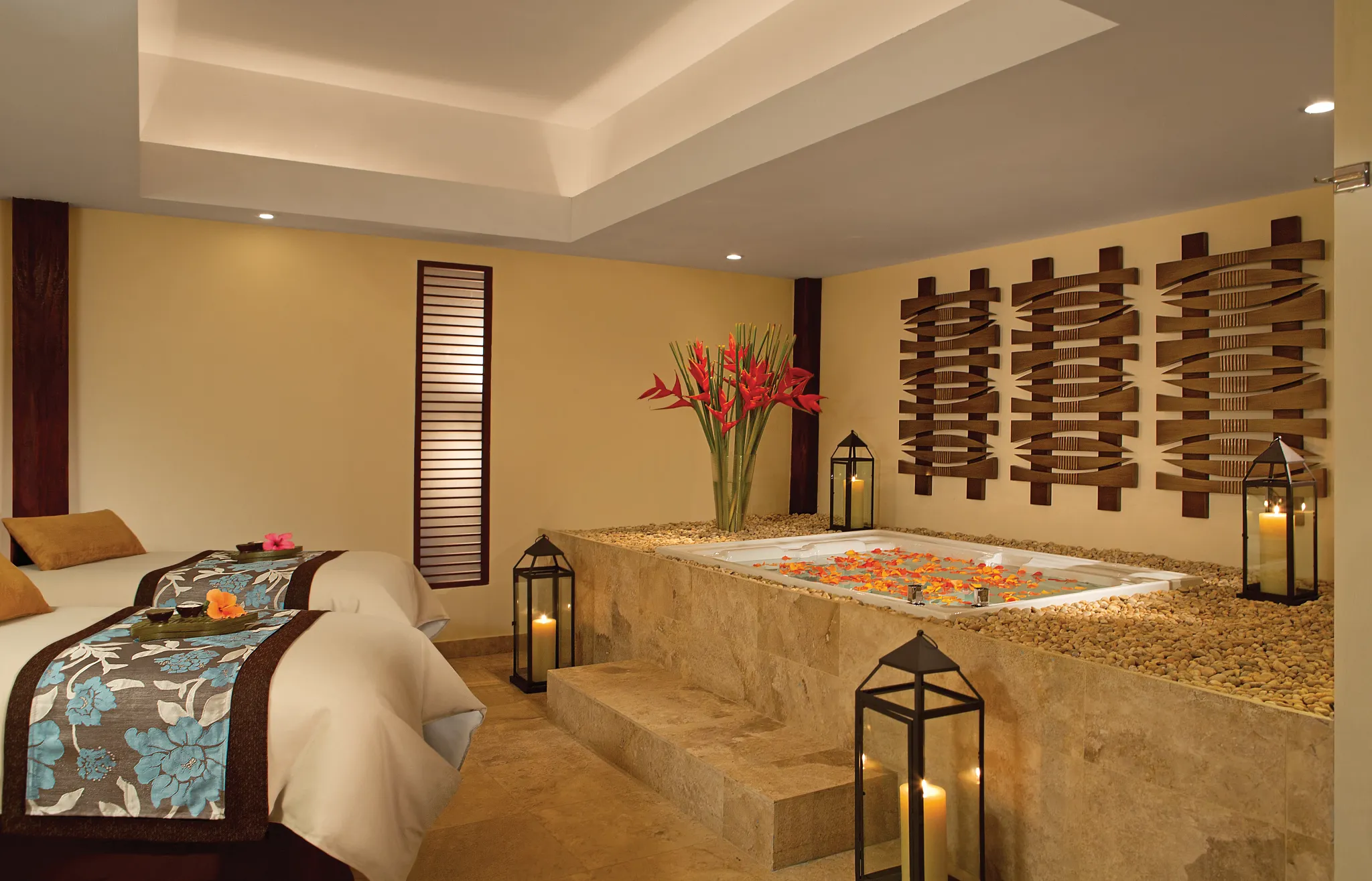Couples spa suite with massage beds and flower-filled whirlpool tub at Dreams Sapphire Resort & Spa.