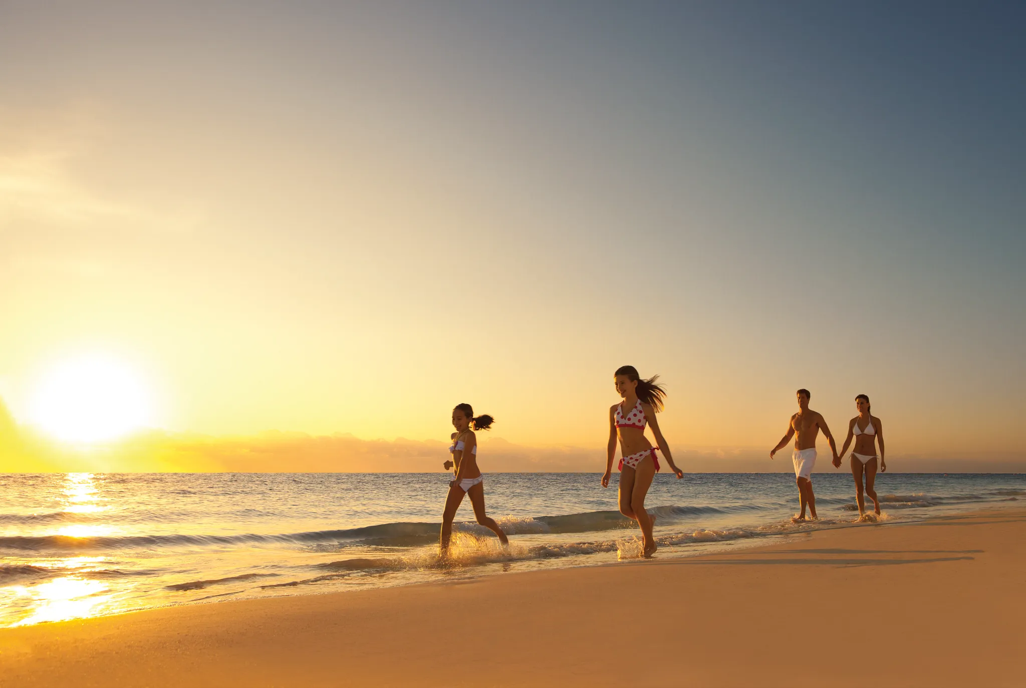 Family walking along the beach at sunset at Dreams Sapphire Resort & Spa in Riviera Maya.