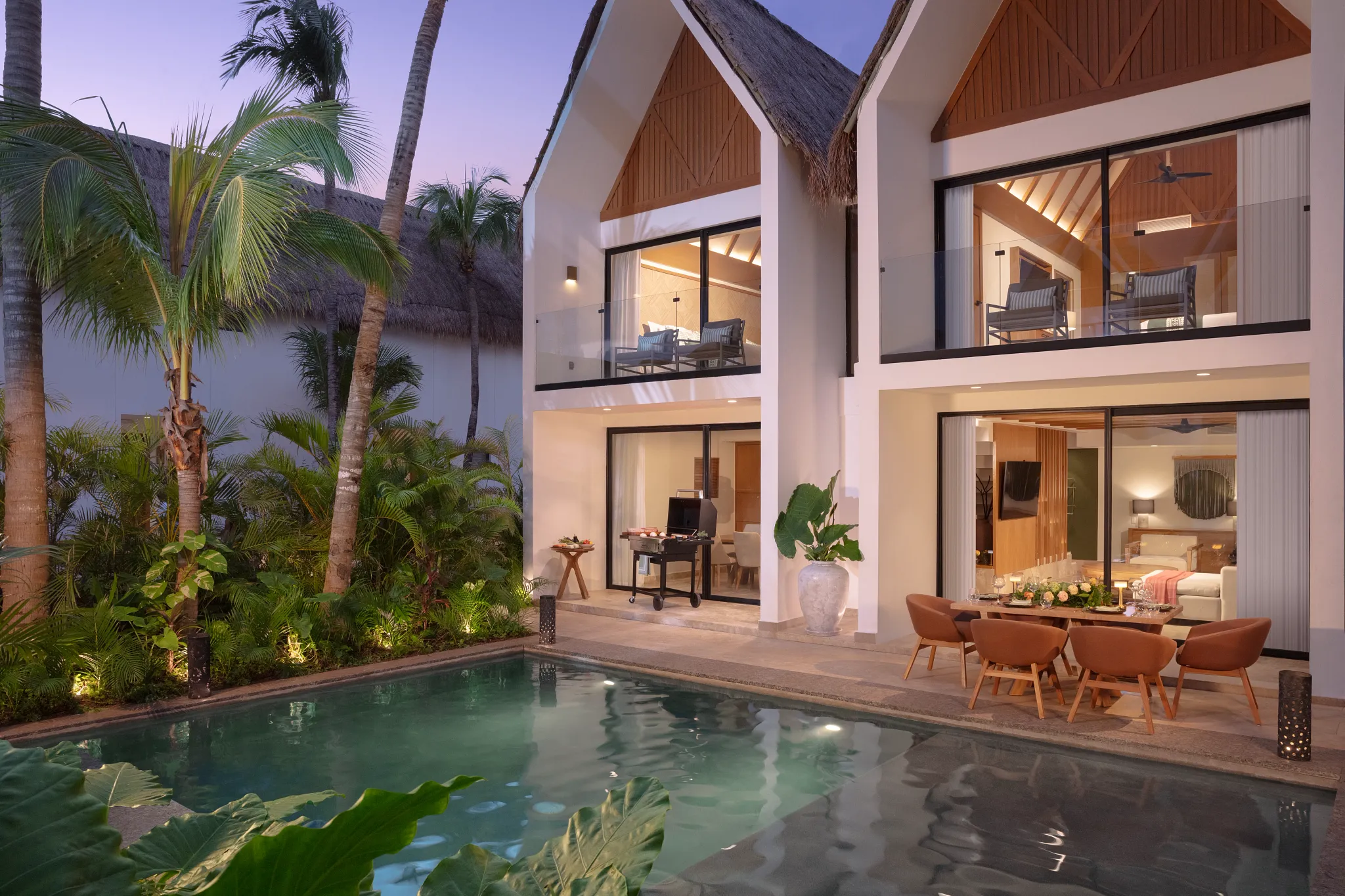 Luxury villa with private pool and outdoor dining area at Dreams Sapphire Resort & Spa illuminated at sunset.