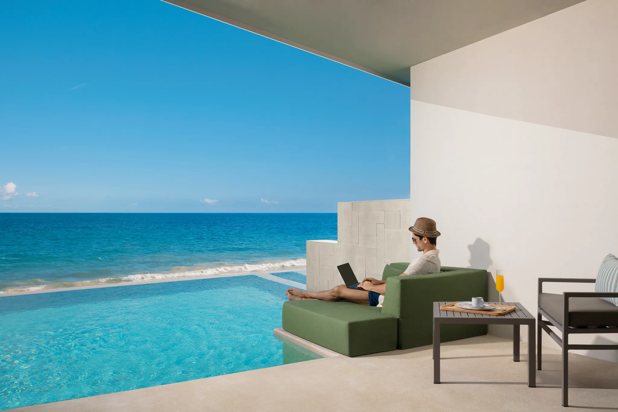 Guest working remotely from an oceanfront suite terrace with a private plunge pool at Dreams Sapphire Resort & Spa.