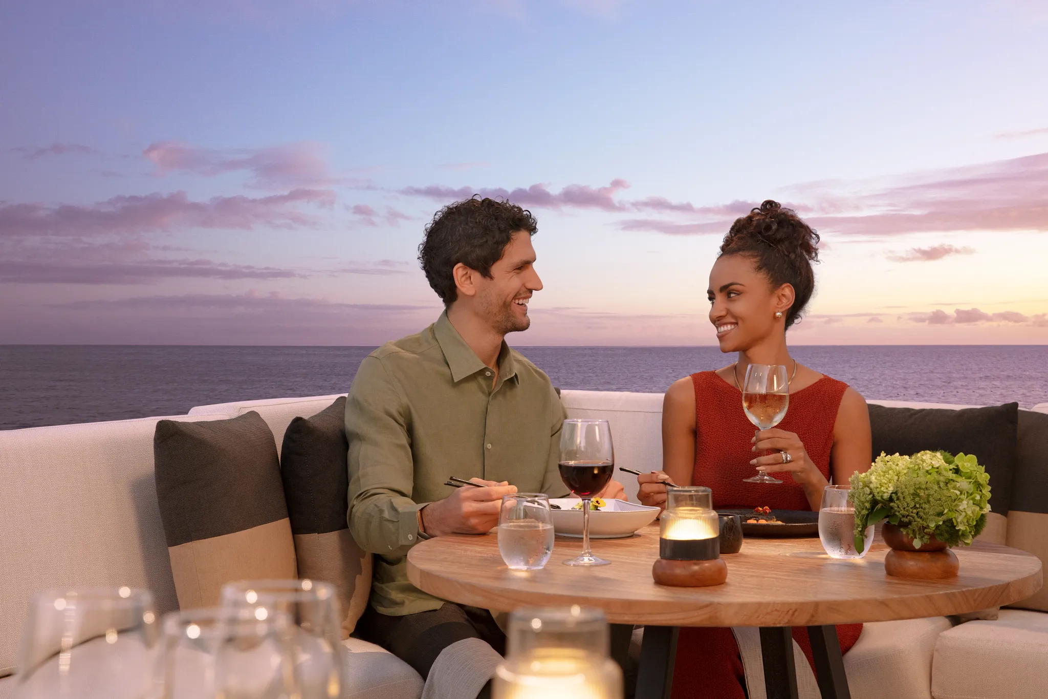 Couple enjoying a romantic dinner with ocean views at Dreams Sapphire Resort & Spa during sunset.