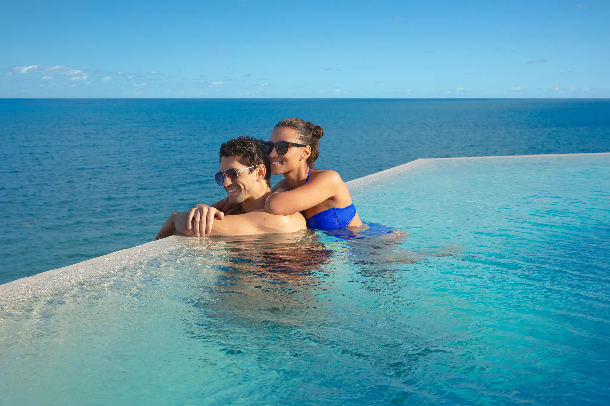 Couple relaxing together in a rooftop infinity pool overlooking the Caribbean Sea at Dreams Sapphire Resort & Spa.
